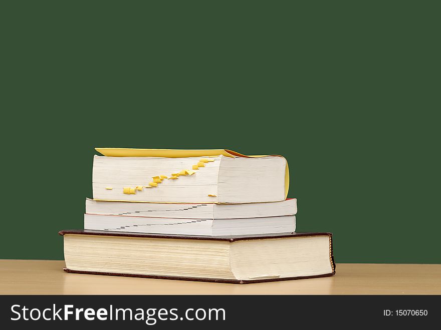 Stack of books with apple in front of green chalkboard. Stack of books with apple in front of green chalkboard