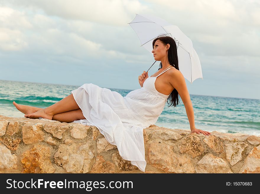 Coastline sitting woman with umbrella