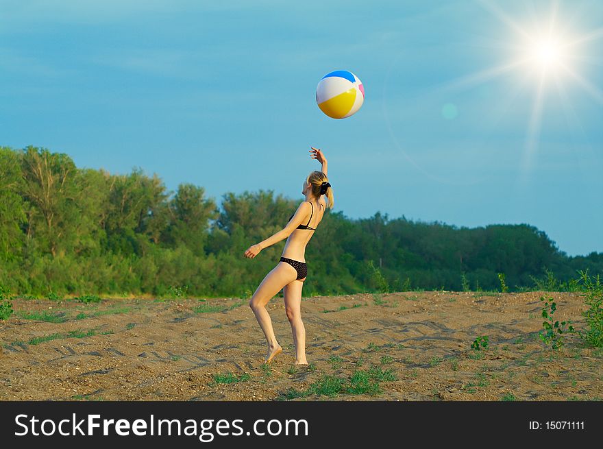 Young girl playing with a ball on the sandy beach