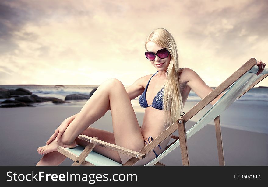 Beautiful woman sitting on a deckchair at the beach. Beautiful woman sitting on a deckchair at the beach