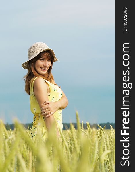 Model in hat smiling in field. Model in hat smiling in field