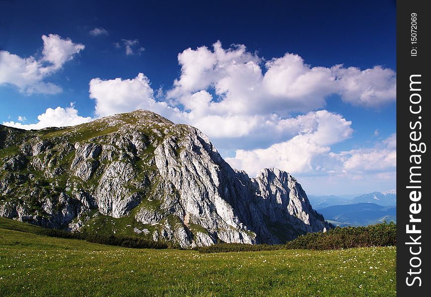 Rock with blue sky and clouds and  meadow with fowers. Rock with blue sky and clouds and  meadow with fowers