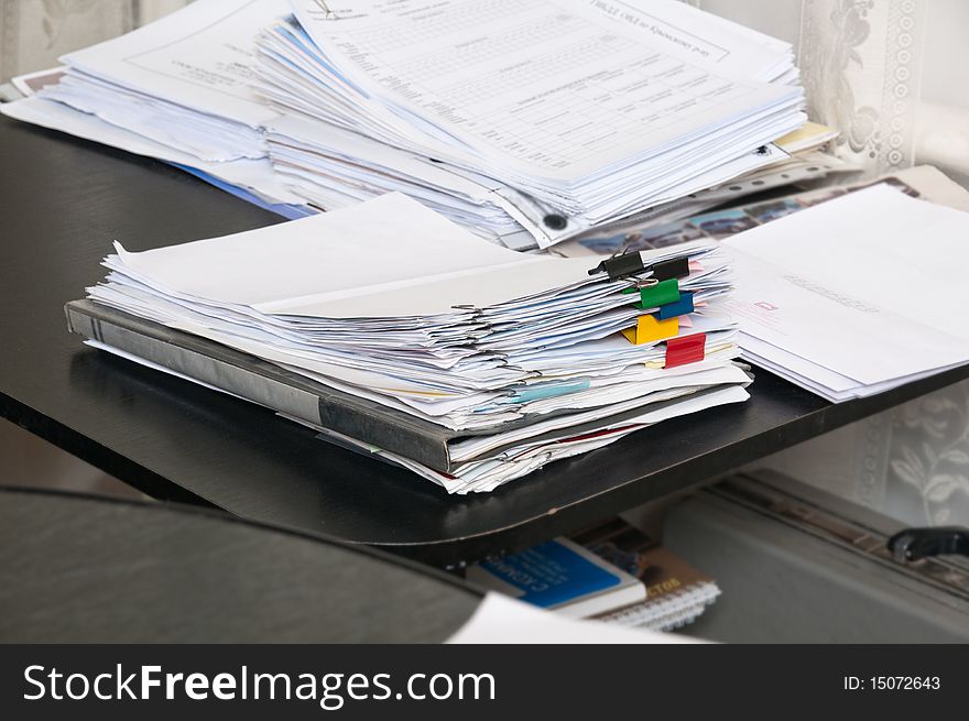 Two piles of various documents on a table at office.