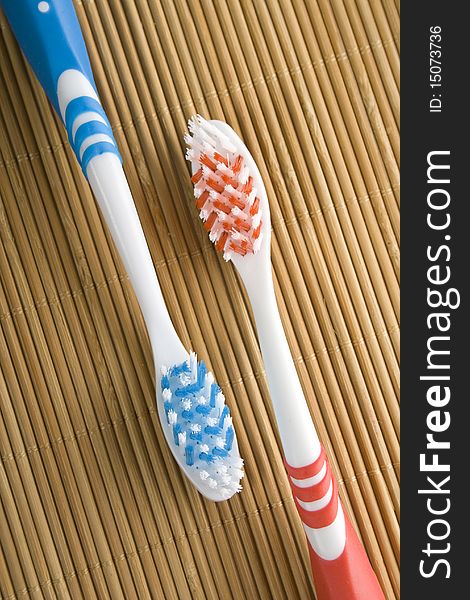 Red and blue toothbrushes lying on a wooden surface