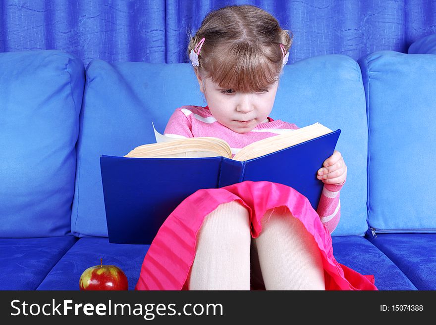 Girl reading book with apple at sofa