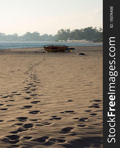 A lost boat on a beach. Footsteps lead from the boat, suggesting it is still in use. A lost boat on a beach. Footsteps lead from the boat, suggesting it is still in use.