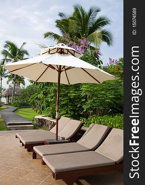 Sunshade and chaise longue in tropical resort.