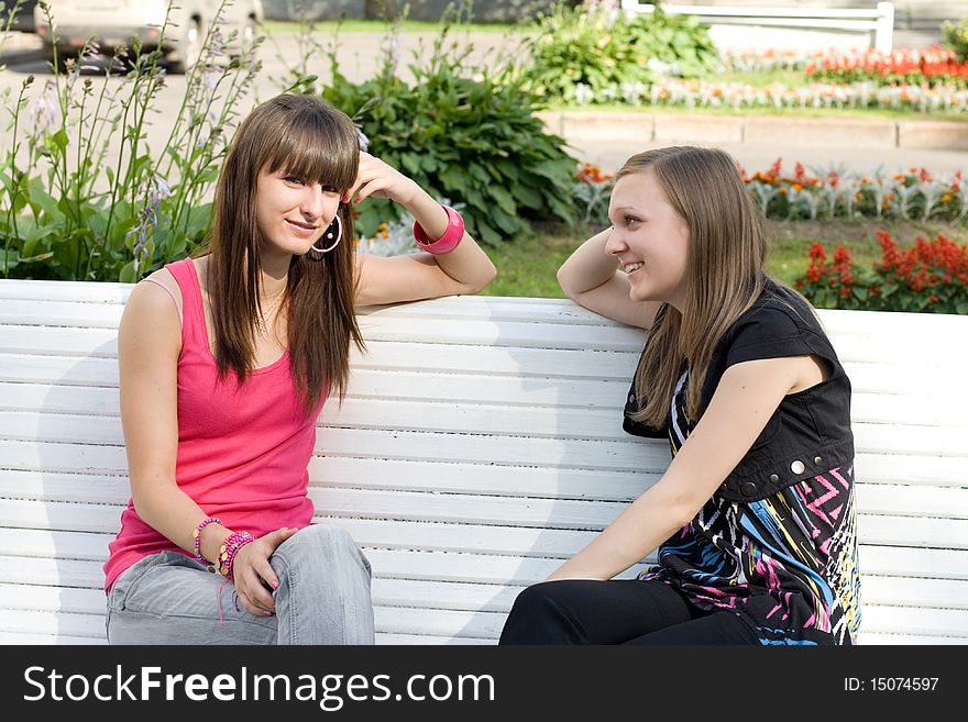 Two female friends sitting on bench