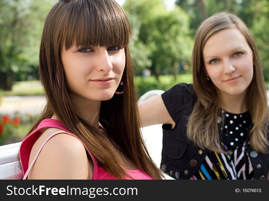 Two female friends sitting on bench