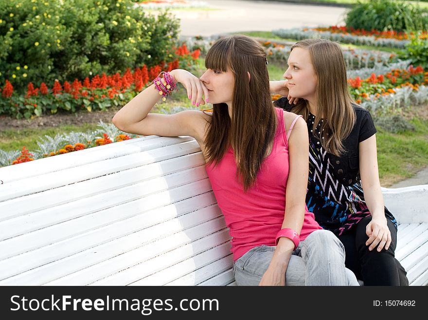 Two female friends sitting on bench