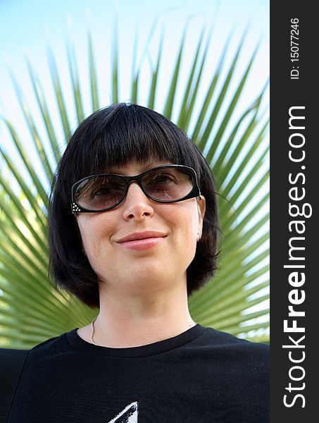 Portrait of woman in sunglasses and palms on background