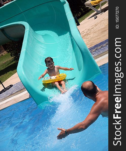 Father catches child on water slide, happy boy