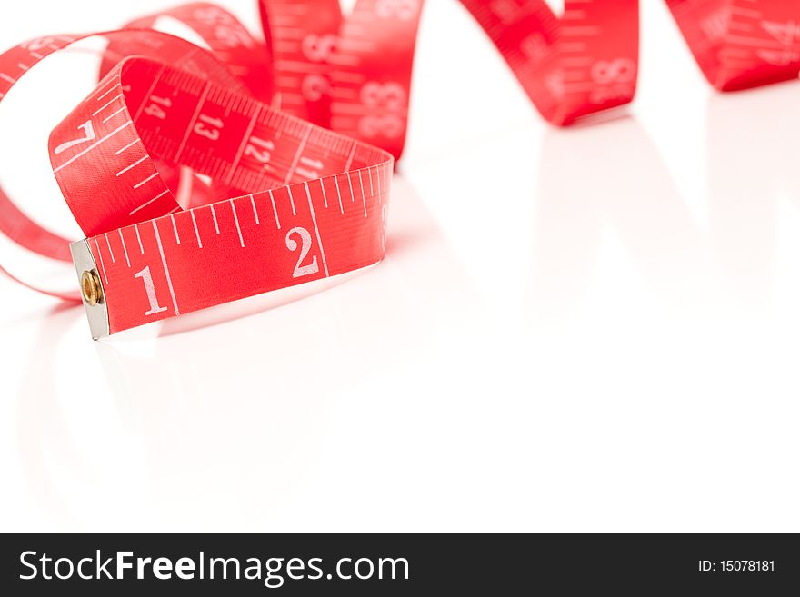 Red Measuring Tape Isolated on a White Reflective Surface. Red Measuring Tape Isolated on a White Reflective Surface.