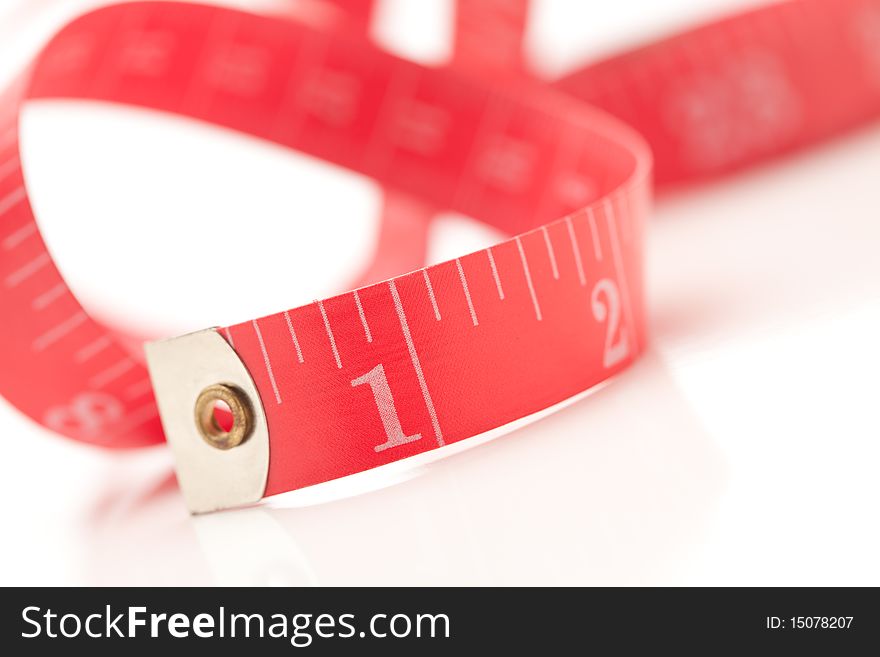 Red Measuring Tape Isolated on a White Reflective Surface. Red Measuring Tape Isolated on a White Reflective Surface.