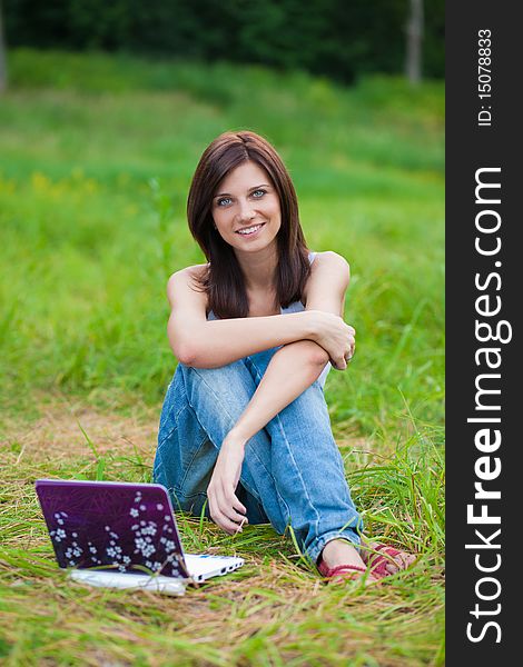 Brunette student girl in the park with notebook on grass