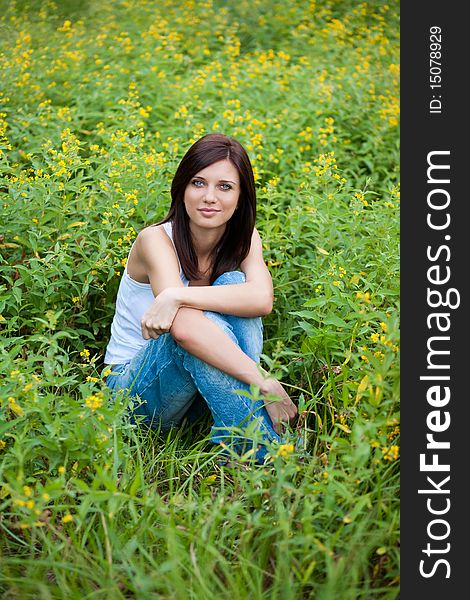 Brunette  girl in jeans in the park on grass