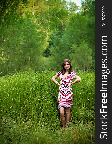 Beautiful brunette girl in dress in green park