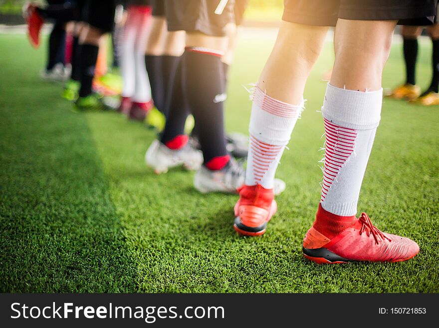Boy soccer players are put multi color sport shoes and standing on green artificial turf with coach before training and start game. sport background