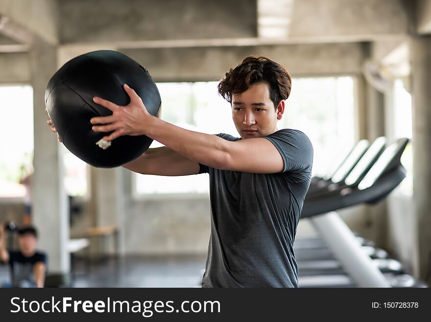 Man swing medicine ball in fitness gym