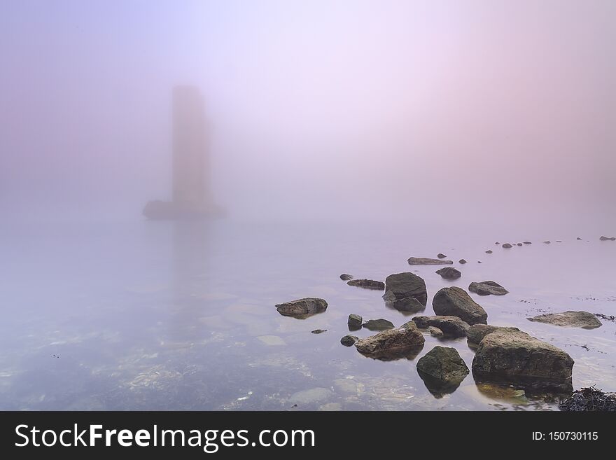 Pillar of a storm surge barrier in fog during sunset