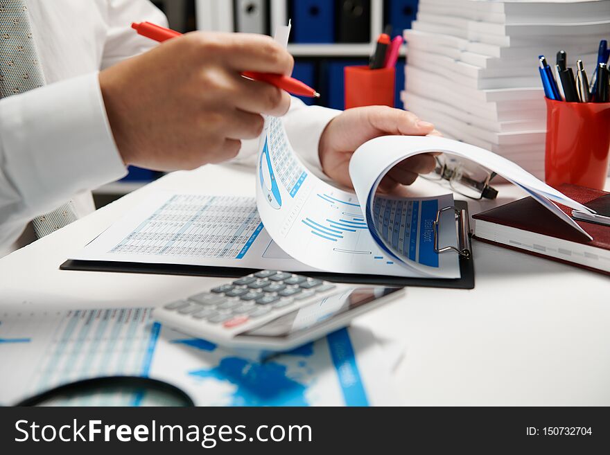 Businessman working and calculating, reads and writes reports. Office employee, table closeup. Business financial accounting