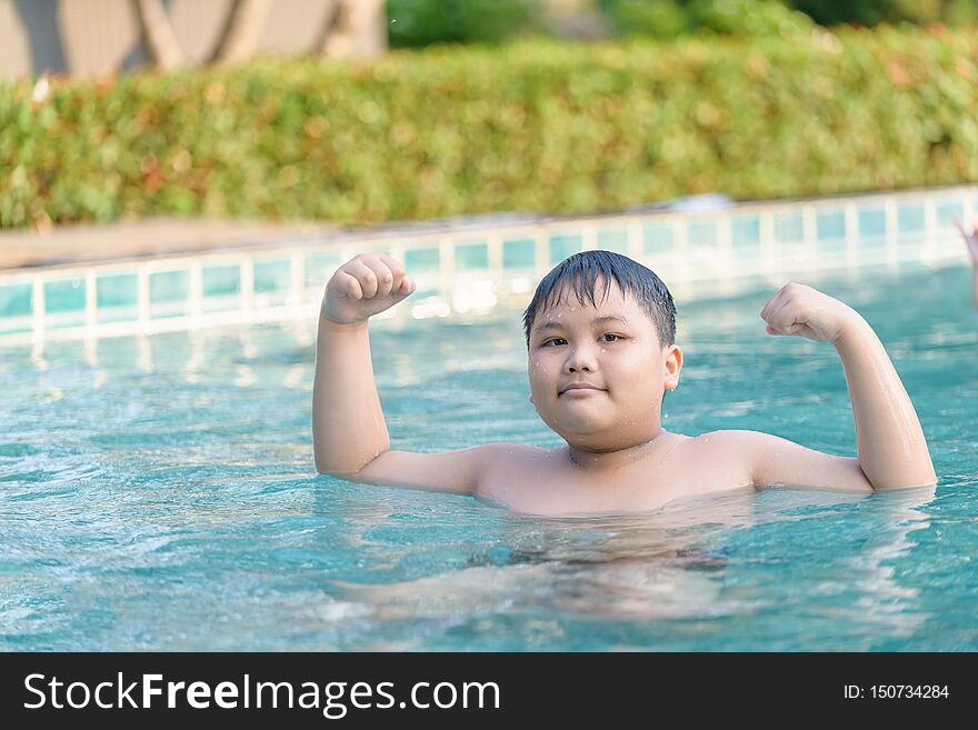 Obese fat boy show muscle in swimming pool, exercise and healthy concept