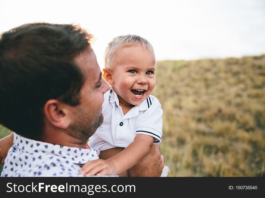 Smiling toddler hugging his father and holding his neck