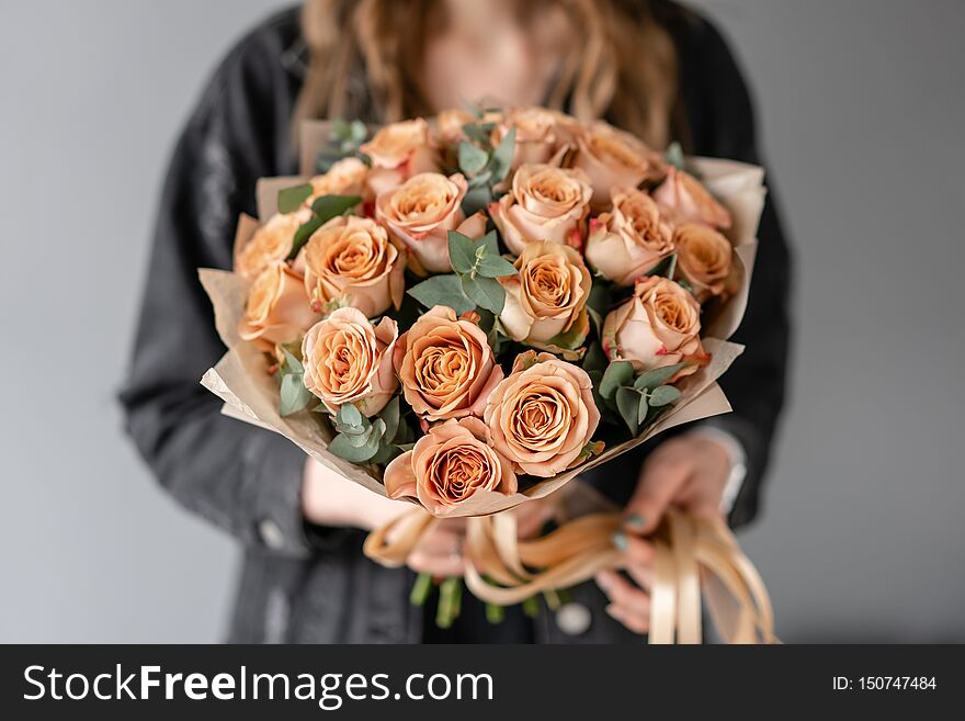 Flowers coffee color, cappuccino roses with eucalyptus. Small Beautiful bouquets in woman hand. Floral shop concept