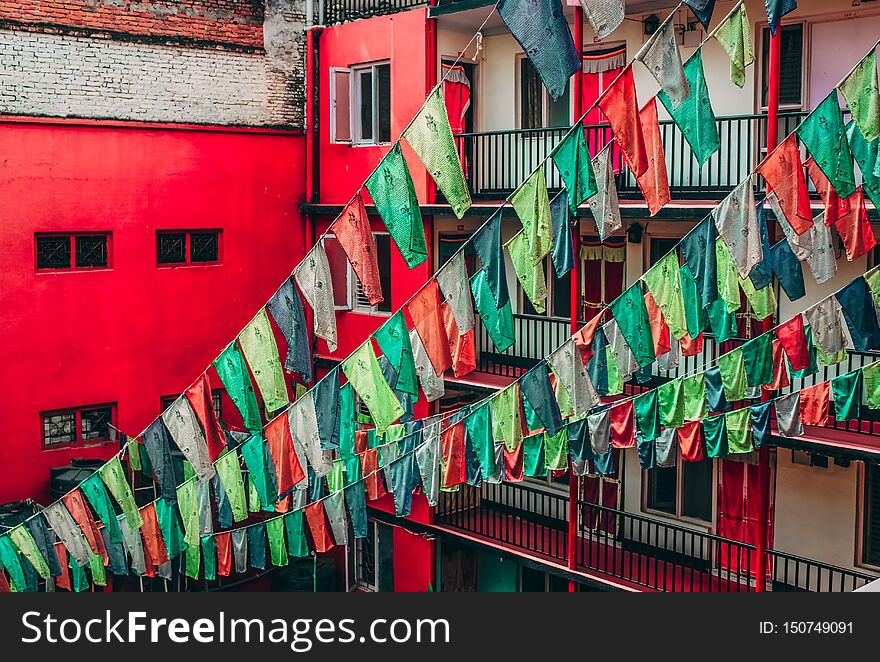 A large number of Buddhist prayer flags tied to laundry ropes in a residential area in Nepal