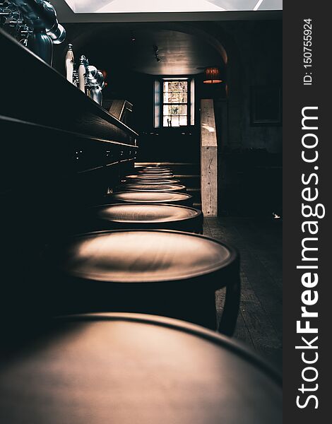 Dramatic shot of wooden stools in a row at the bar of an old English Pub in the North of England.