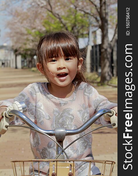 Japanese girl riding on the bicycle under cherry blossoms