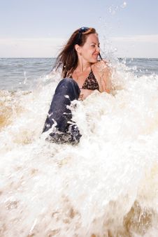 Young Woman Sits In Water Splashes At The Beach Royalty Free Stock Photo