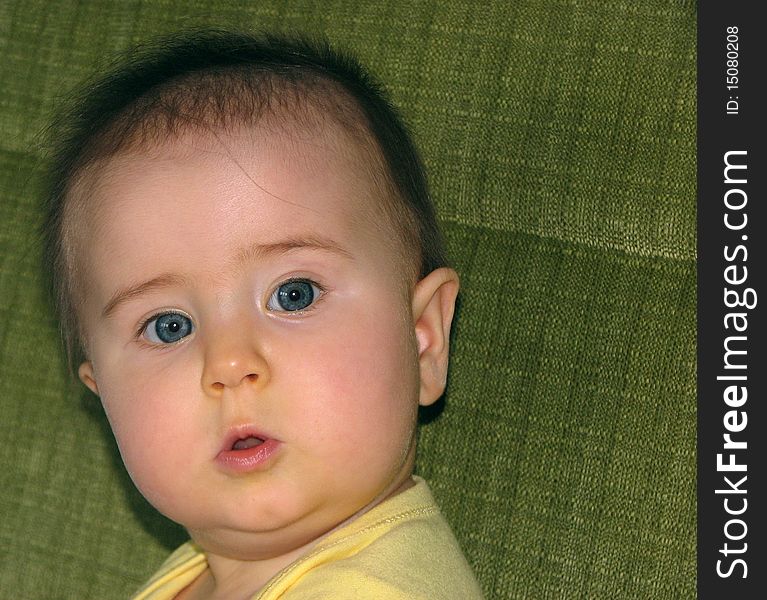 Puzzled-looking toddler sitting on a green sofa