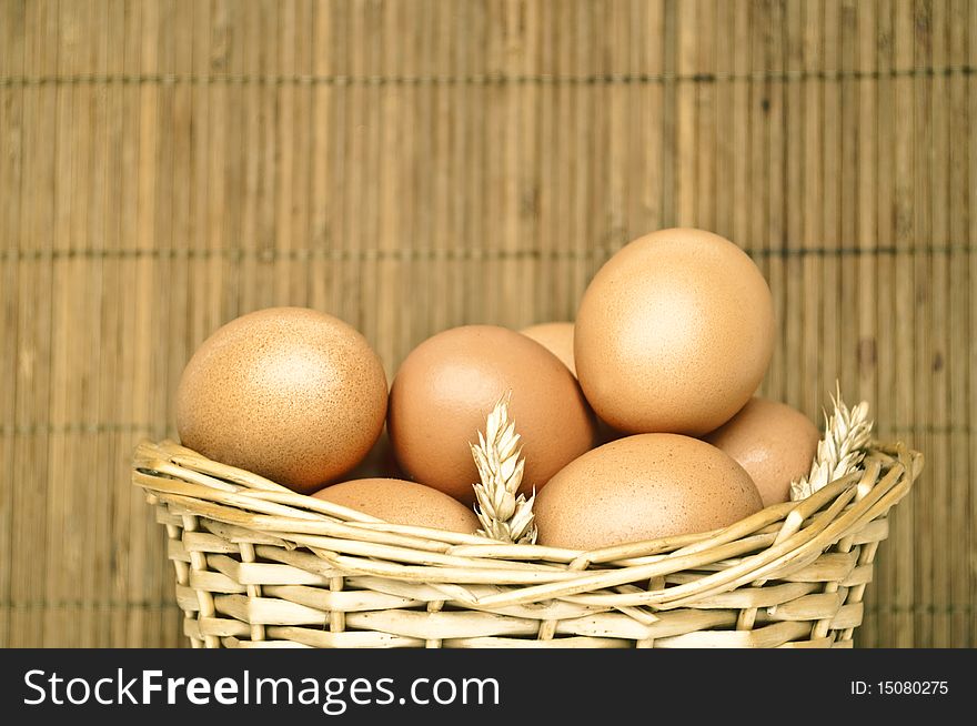 Eggs in wicker basket with ripe ears