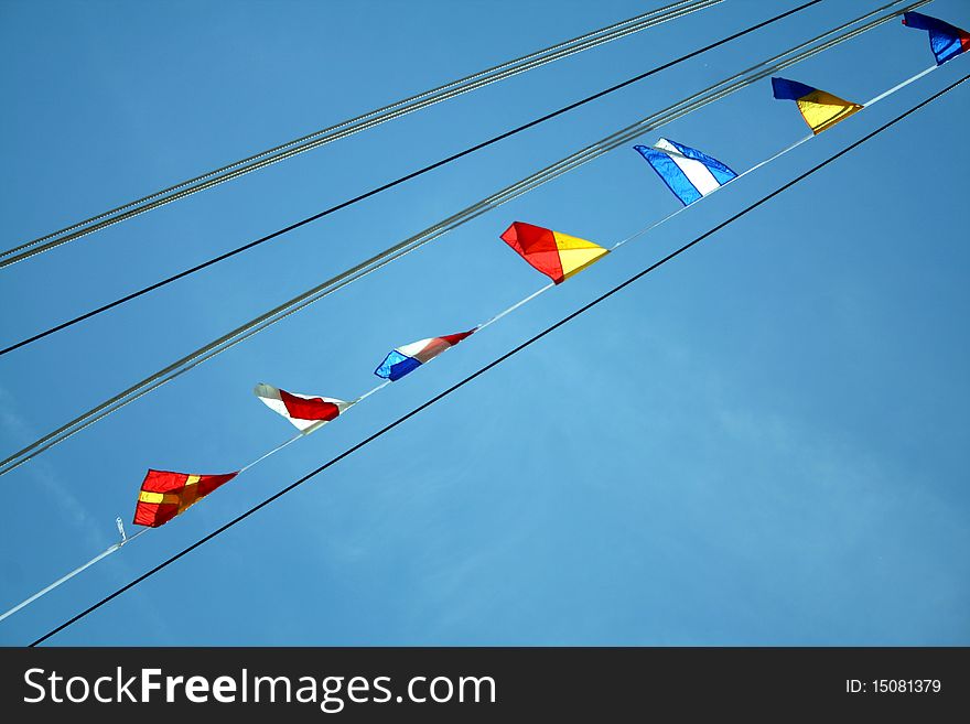 Many small colorful flags on the rope on the background of sky