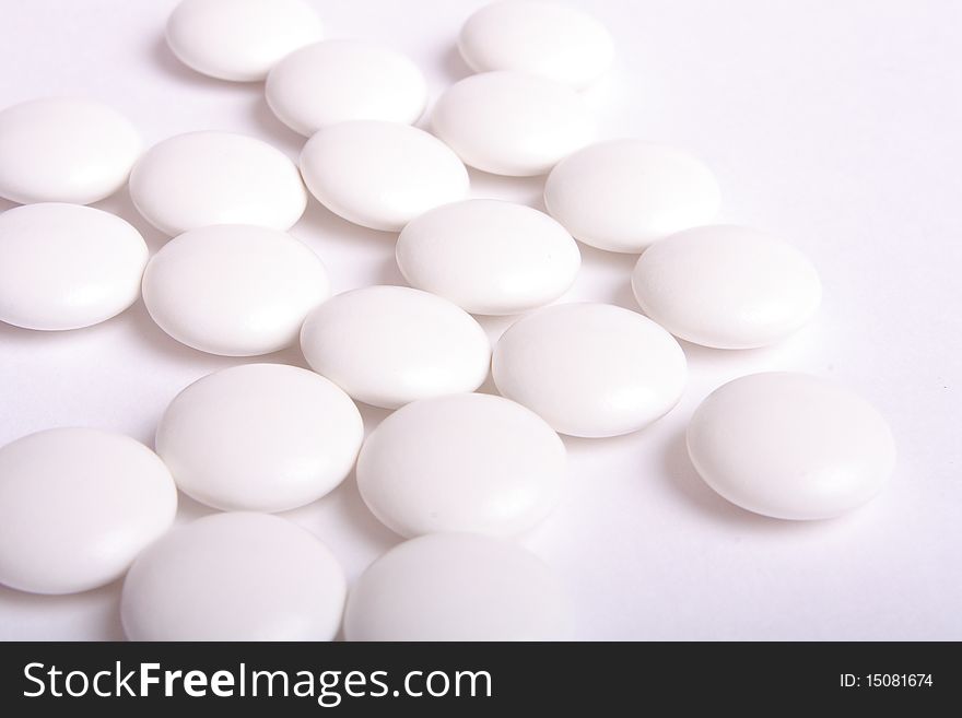 Some white tablets on white background (close up). Some white tablets on white background (close up)