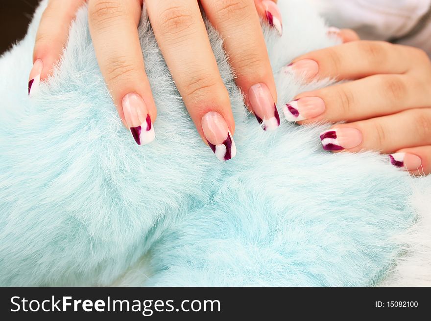 Woman hands with nail art on blue fur background.