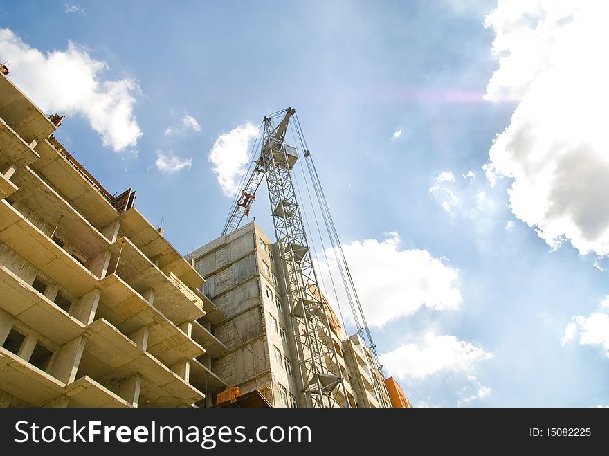 Photos of unfinished housing complex and high-rise construction crane against the blue sky with clouds. Photos of unfinished housing complex and high-rise construction crane against the blue sky with clouds