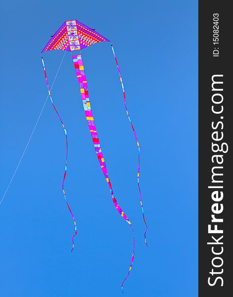 Colorful kite flying high in bright blue sky.