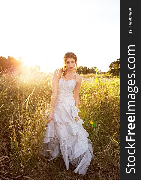 An attractive young woman wearing formal attire is standing in a grass field. Vertical shot. An attractive young woman wearing formal attire is standing in a grass field. Vertical shot.