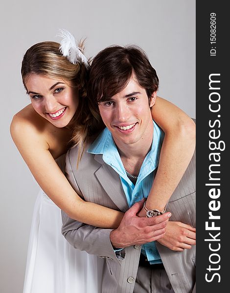 Young woman in a strapless dress has her arms around her boyfriend as the smile at the camera. Vertical shot. Young woman in a strapless dress has her arms around her boyfriend as the smile at the camera. Vertical shot.