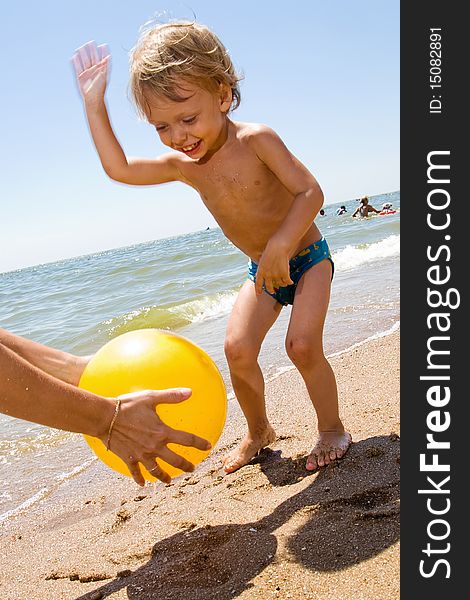 Infant kid plays ball at the sea. Infant kid plays ball at the sea
