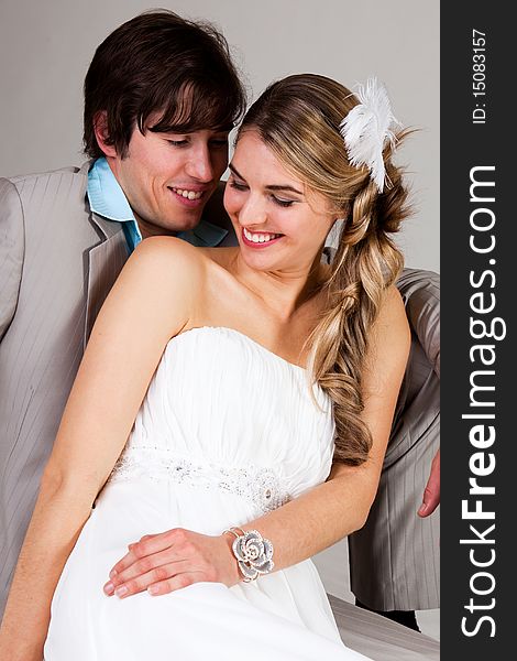 Attractive young couple sitting affectionately together. The man is wearing a suit and the woman is in a strapless dress. Vertical shot. Attractive young couple sitting affectionately together. The man is wearing a suit and the woman is in a strapless dress. Vertical shot.