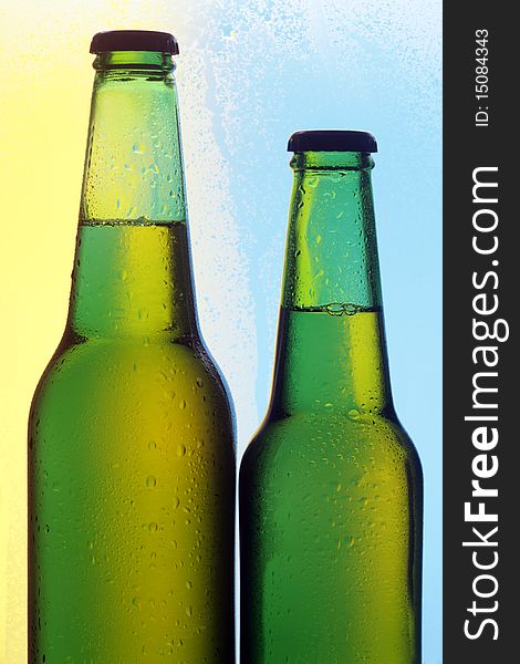 Two beer bottles on a colour background