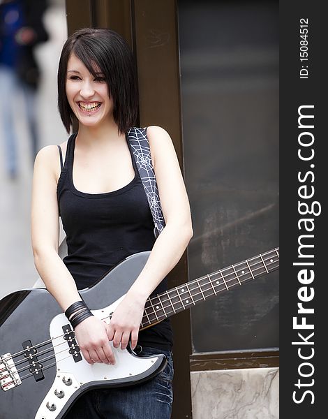 Young cheerful female guitarist on urban background. Young cheerful female guitarist on urban background