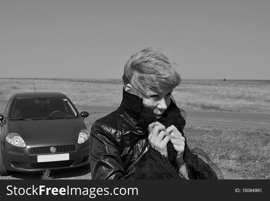 A woman raises his collar to keep warm, afraid ill, horizontal image, caption, freezing the driver who ran out of petrol on the road, gray tones. A woman raises his collar to keep warm, afraid ill, horizontal image, caption, freezing the driver who ran out of petrol on the road, gray tones.