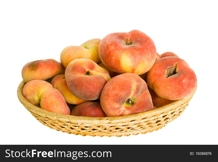 Mountain peaches in wicker wooden bowl in isolated over white. Mountain peaches in wicker wooden bowl in isolated over white