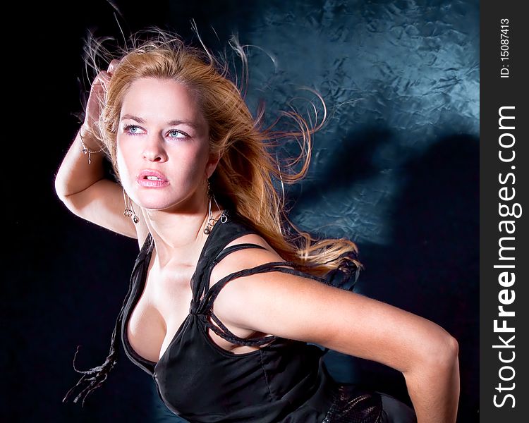 Beautiful blondie woman with spreading hair dancing, black background