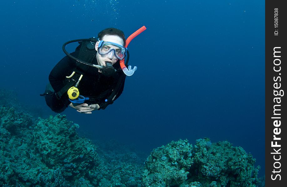 Man scuba diver swims in clear blue water. Man scuba diver swims in clear blue water