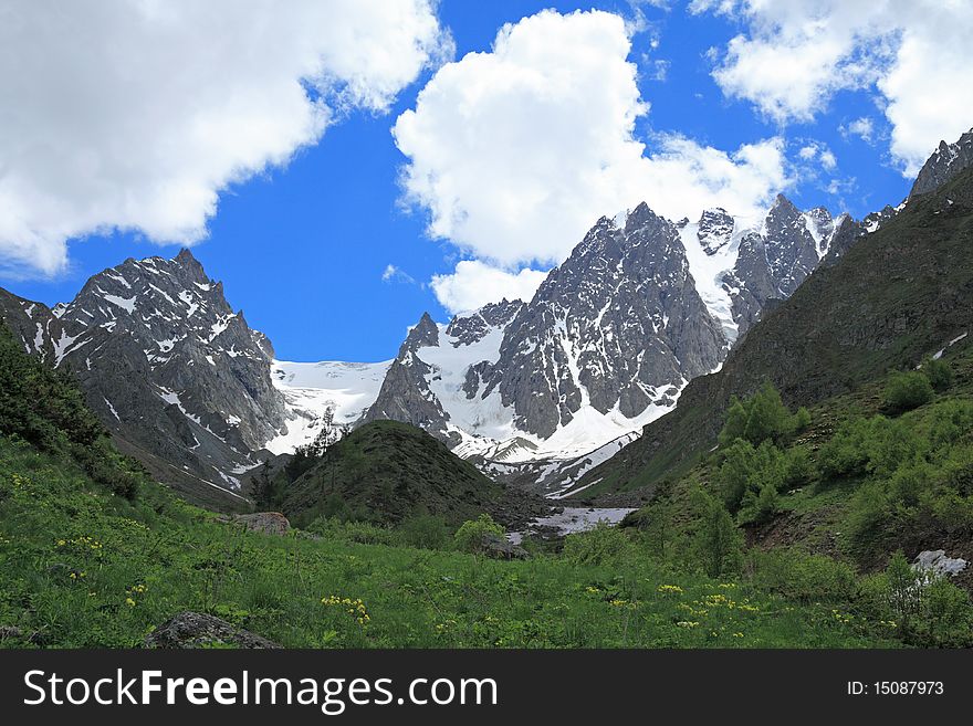 Summer sunny day in a mountain valley. Caucasus. The mountain in the centre is called  peak of aviation. Summer sunny day in a mountain valley. Caucasus. The mountain in the centre is called  peak of aviation